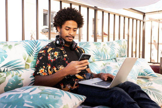 Focused black man browsing smartphone on terrace