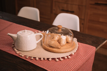 Breakfast in the kitchen. teapot and croissants on table