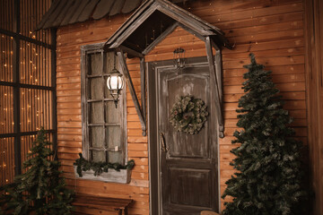 Fototapeta na wymiar Christmas morning. porch a small house with a decorated door with a Christmas wreath. Winter fairy tale
