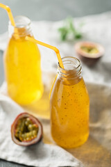 Passion fruit drink with chia seeds in glass bottles with tubes. Grey background
