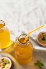 Passion fruit drink with chia seeds in glass bottles with tubes. Grey background