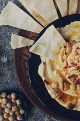 Traditional homemade middle eastern dish - hummus decorated with chickpeas, garlic, olive oil and spices on dark stone table