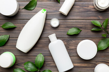 Organic cosmetic products with green leaves on wooden background. Flat lay