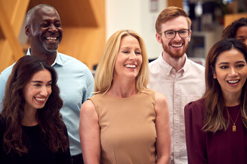 Fototapeta premium Portrait Of Smiling Multi-Cultural Business Team Standing In Modern Open Plan Office