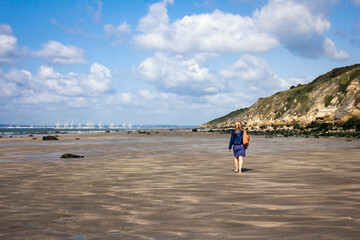 woman walking on the beach, le havre port in distance