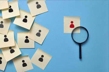 A magnifying glass aimed at the drawing of a person. A symbol of finding a good job candidate. The employer is looking for an employee