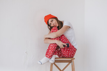 smiling funny girl in a red hat and Christmas pajamas sitting in bed with white sheets. holidays...