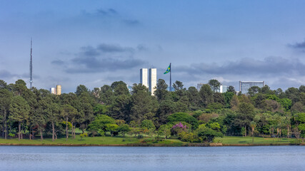 Fototapeta premium View of Brazilian House Parliament from Lake Paranoa in Brasilia, Brazil surrounded by woods. Cityscape.