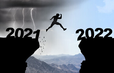 Man jumps over abyss with thunderstorm in background and inscription 2021 and 2022.
