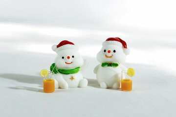 Christmas background. Happy snowmen with tropical drinks, on a white background with hard shadows. Merry christmas and happy new year greeting card. Isolated Christmas snowmen wearing Santa Claus hat.