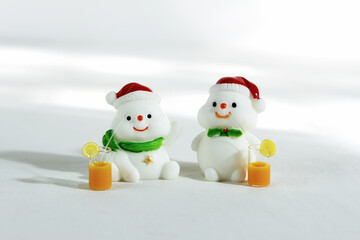 Christmas background. Happy snowmen with tropical drinks, on a white background with hard shadows. Merry christmas and happy new year greeting card. Isolated Christmas snowmen wearing Santa Claus hat.