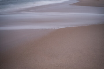 Soft focus beach foam rolls onto an empty beach during an Atlantic storm