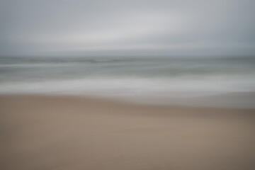 Fototapeta na wymiar Soft focus beach foam rolls onto an empty beach during an Atlantic storm