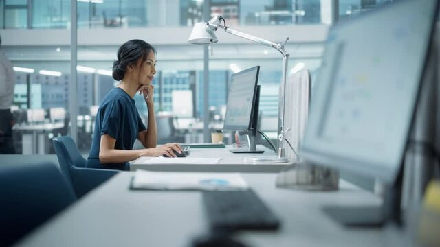 In Big Diverse Corporate Office: Portrait of Beautiful Asian Manager Using Desktop Computer, Businesswoman Managing Company Operations, Analysing Statistics, Commerce Data, Marketing Plans.