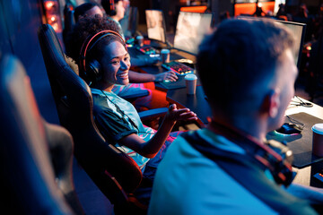 Happy African female sitting close to teammate and talk to him during participation in online gaming arena in cyber club © Yaroslav Astakhov