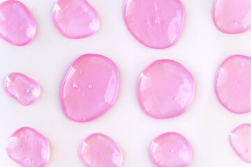 Pink doses of acid, hyaluronic moisturizing serum or gel isolated on white background. Abstract backdrop pattern. Beauty product wallpaper. Cosmetics or healthcare protection concept. 