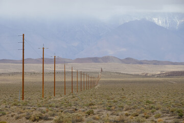 power lines stretching across the empty and desolate California desert with the snow covered Sierra Nevada mountains as a backdrop