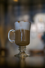 Glass cup with latte is on the table in coffee shop. Glass with caramel cappuccino on the table in the restaurant. Photo for the menu, advertising