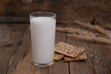 glass of milk with cereal cracker or cookies on wooden background