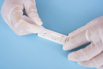 Close up medical technician hand taking a swab for corona virus sample from potentially infected.Covid-19 laboratory test.Antigen test kit for self collect nose swab on blue background.