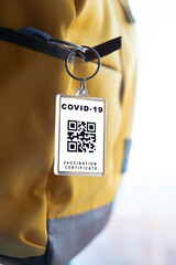 The Covid 19 vaccination certificate is printed on a keychain and hangs on a backpack