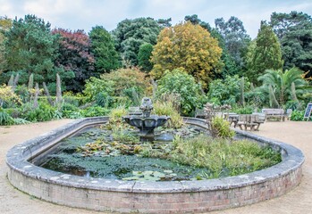 fountain and pond in Ventnor Botanic Gardens Isle of Wight Hampshire England with Autumnal coloured trees in the background