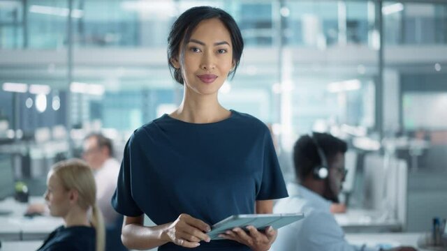 Successful Businesswoman in Stylish Dress Using Tablet Computer, Standing in Modern Diverse Office Working on Financial, Business and Marketing Projects. Portrait of Beautiful Asian Manager.