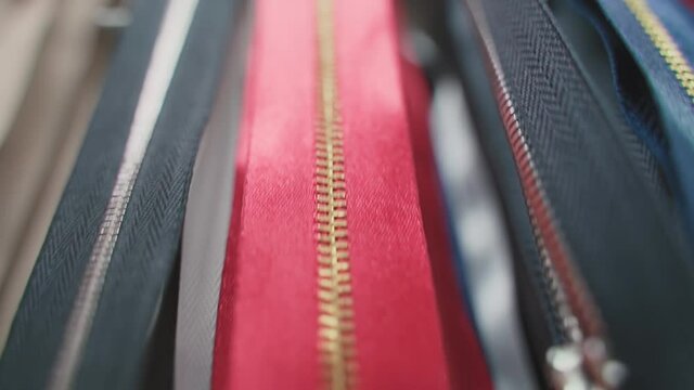 zippers hanging on the wall in a manufacturing shop. Slide fastener red, yellow, white, black color sale in stores. Texture background