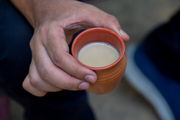 Person holding a cup of tea in natural clay cup