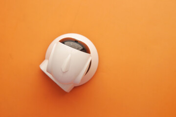 CCTV security camera operating on light orange background 