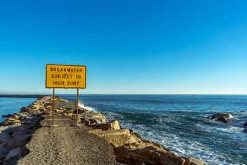 Breakwater Subject to High Surf sign in Dana Point, California - obrazy, fototapety, plakaty