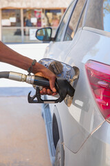 African man driver hand refilling and pumping gasoline oil the car with fuel at station