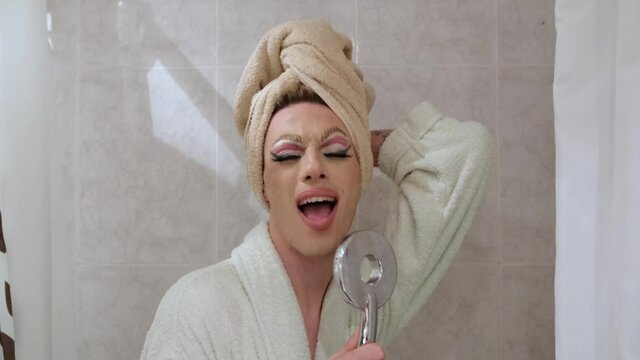 Drag queen person singing using shower head as a microphone.