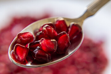 pomegranate seeds on a metal steel spoon
