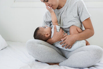 Loving mom holding her 6 months old baby inside bedroom - Mother and child love