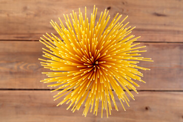 A vertical bunch of raw spaghetti tied with string. Bundle on a wooden background. View from above.