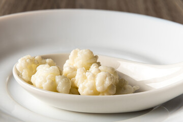 Kefir grains on a white spoon znf plate, close up