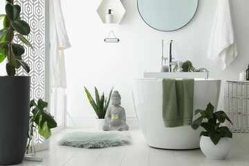 Stylish bathroom interior with modern tub, houseplants and beautiful decor. Home design