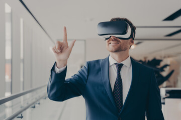 Cheerful businessman dressed formally using vr headset at work
