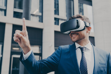 Smiling bearded businessman with stubble wearing VR glasses, viewing something in virtual reality