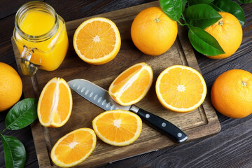 Naklejka na ściany i meble Fresh orange juice in a glass on a wooden background. Fresh Orange fruits with green leaves. Healthy vegan food. Vitamins food.Ripe oranges.Flat lay.