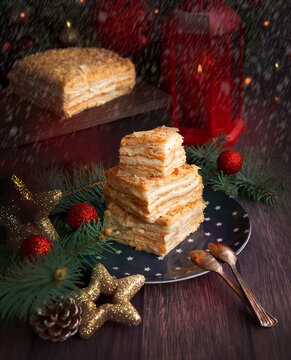 Classic cake "Napoleon". Layered, with custard, cut into pieces. Cake on a wooden background with branches of a Christmas tree. new year,