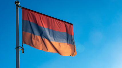 Variant of the flag of Armenia with alternative colors on the flagpole waving in the wind on a blue background.