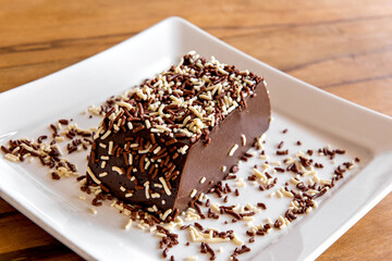 Chocolate pudding with sprinkles, delicious chocolate dessert on wooden table.