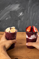 Man holding Brazilian Frozen Açai Berry Ice Cream Smoothie in plastic cup with Strawberries and...