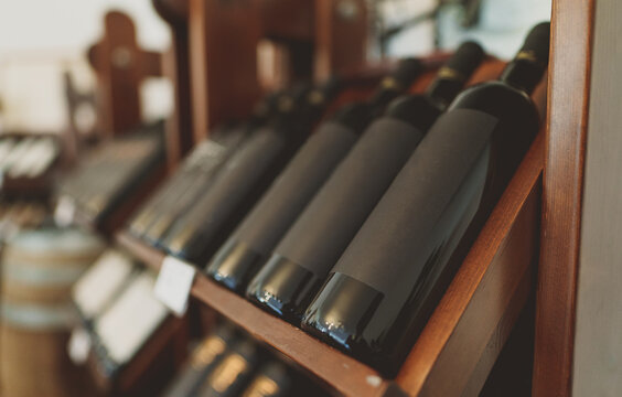 Red wine bottles stacked on wooden rack.