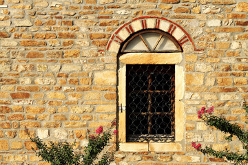 Texture background of old brickwall with ancient window and flowers in Greece