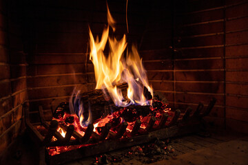 Christmas time, cozy fireplace. Wood logs burning, fire bricks background, relaxation and warm home