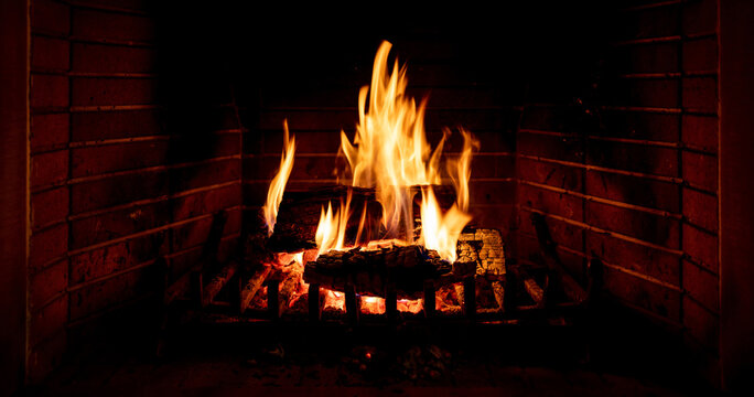 Christmas time, cozy fireplace. Wood logs burning, fire bricks background, relaxation and warm home