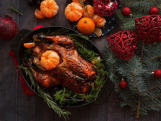 Roast Christmas duck with oranges and tangerines on a rustic wooden table decorated with fir branches - 469970124